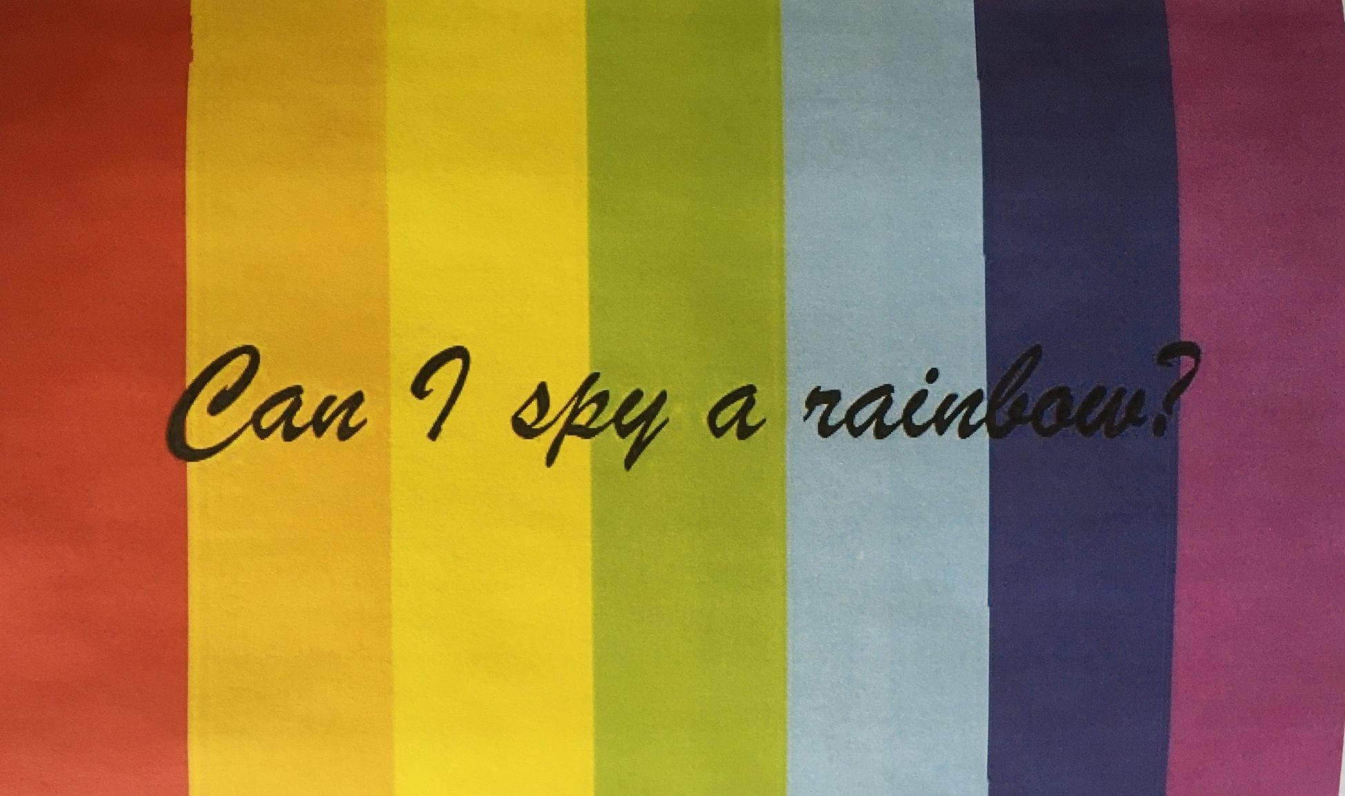 Photo of a card with vertical stripes in rainbow colours and the text 