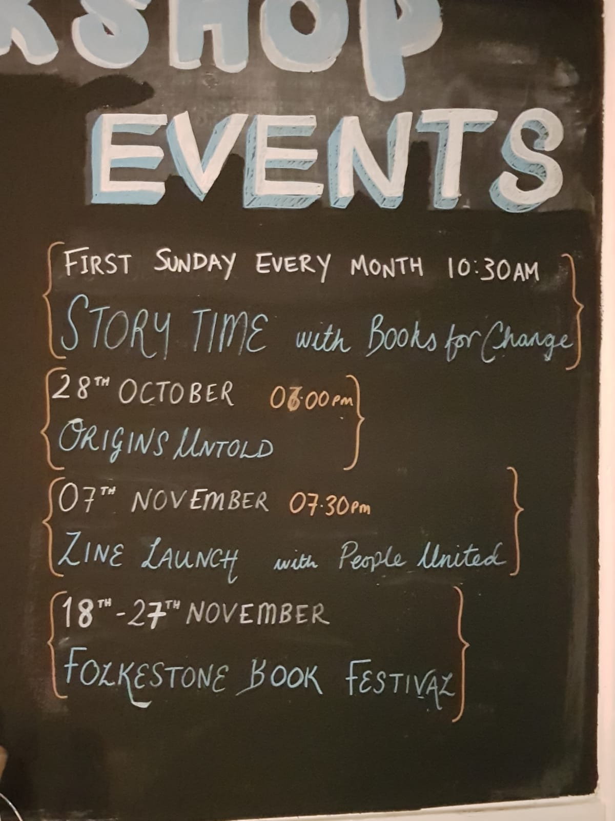 Photo of a large chalk board with part of the Folkestone Bookshop logo drawn at the top and a list of events underneath, including 